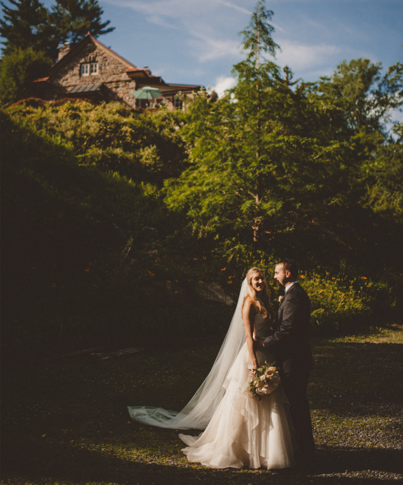 bride and groom hugging standing in front of a hill with a building on top of it.