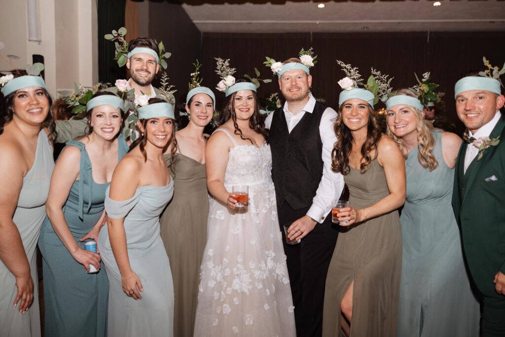 Newlyweds pose with guests in floral headdresses.