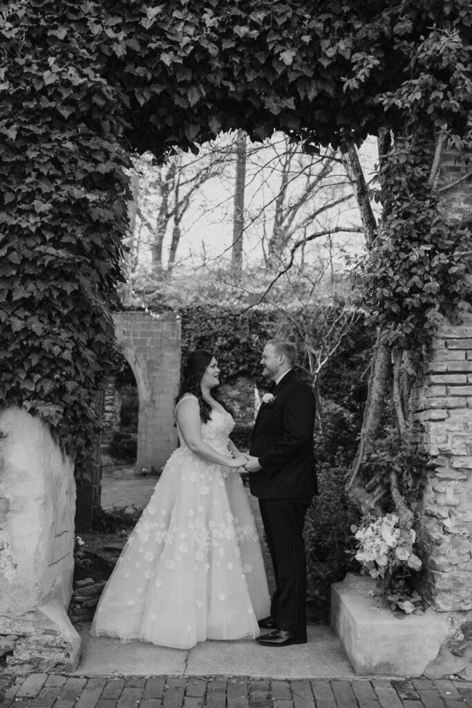 Newlyweds holding hands under the ivy archway.