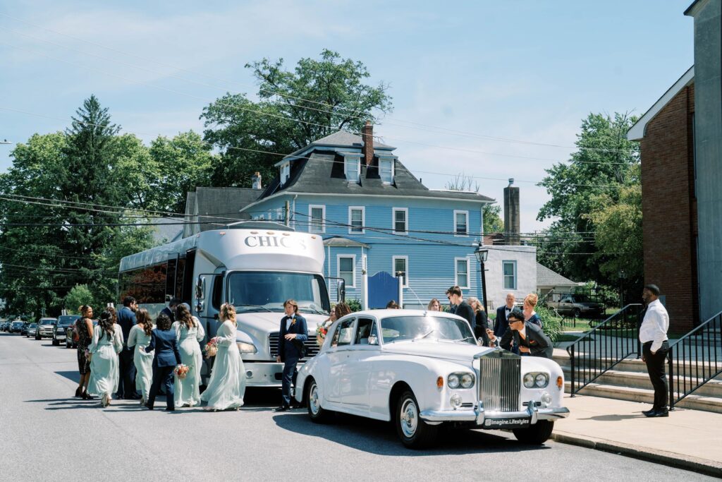 Bridal party with their Rolls Royce car and party bus.