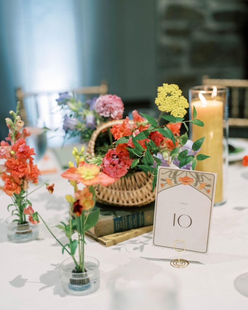 Floral basket centerpeice with a candle and book.