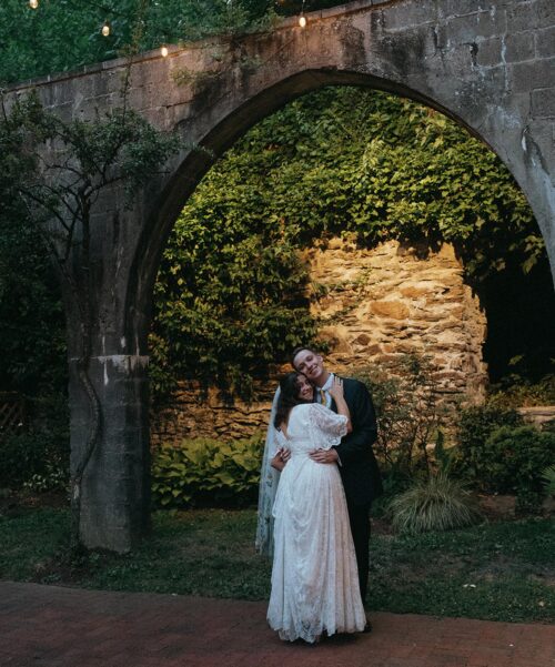 Newlyweds dance in the garden under the archway.