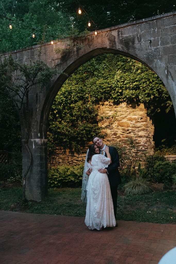 Newlyweds dance in the garden under the archway.