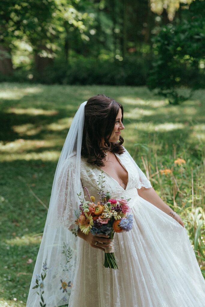 Bride posing in her dress in the grassy garden.